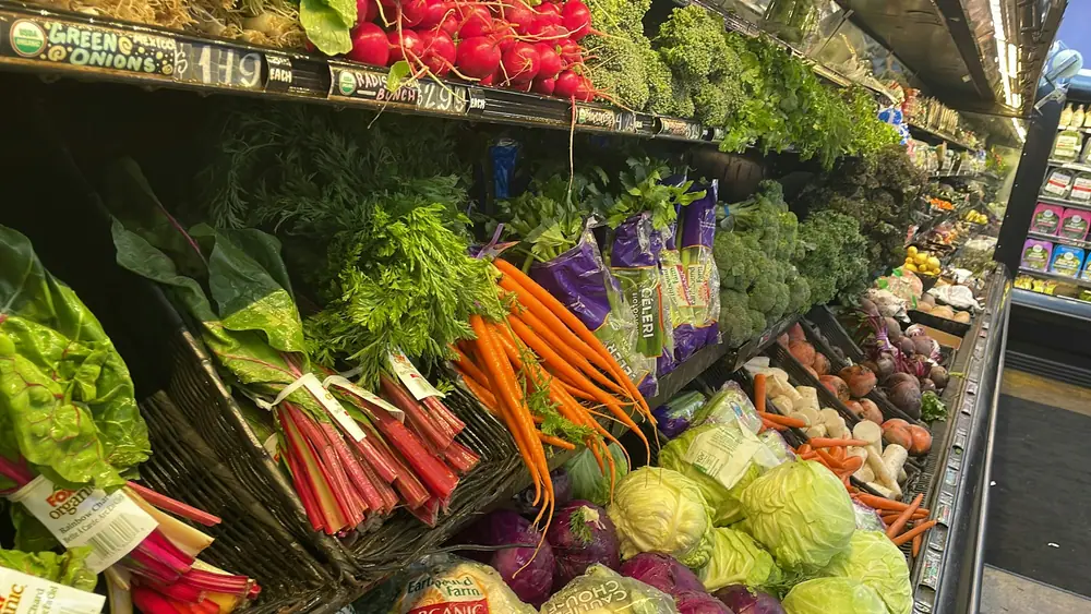 Verduras frescas, zanahorias y hortalizas de hoja apiladas en un puesto de mercado