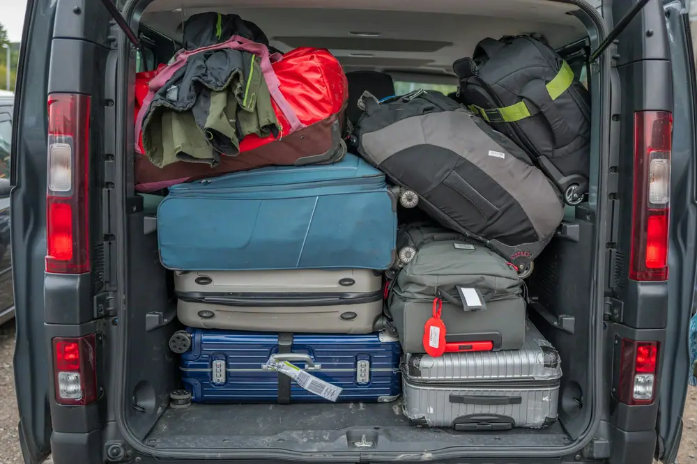 Parte trasera de una furgoneta llena de maletas, bolsas de viaje y mochilas