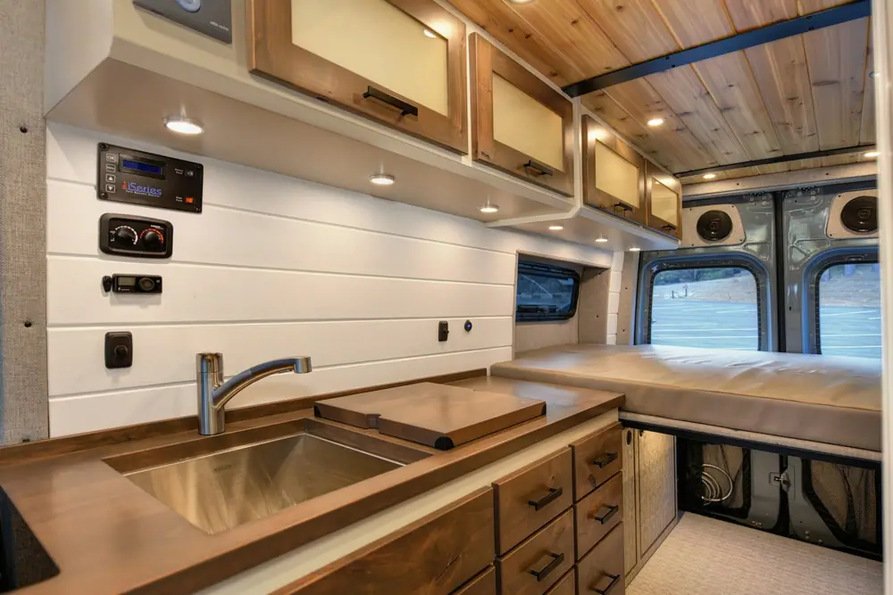 Cocina de una camper con fregadero de acero, cajones de madera y altillos